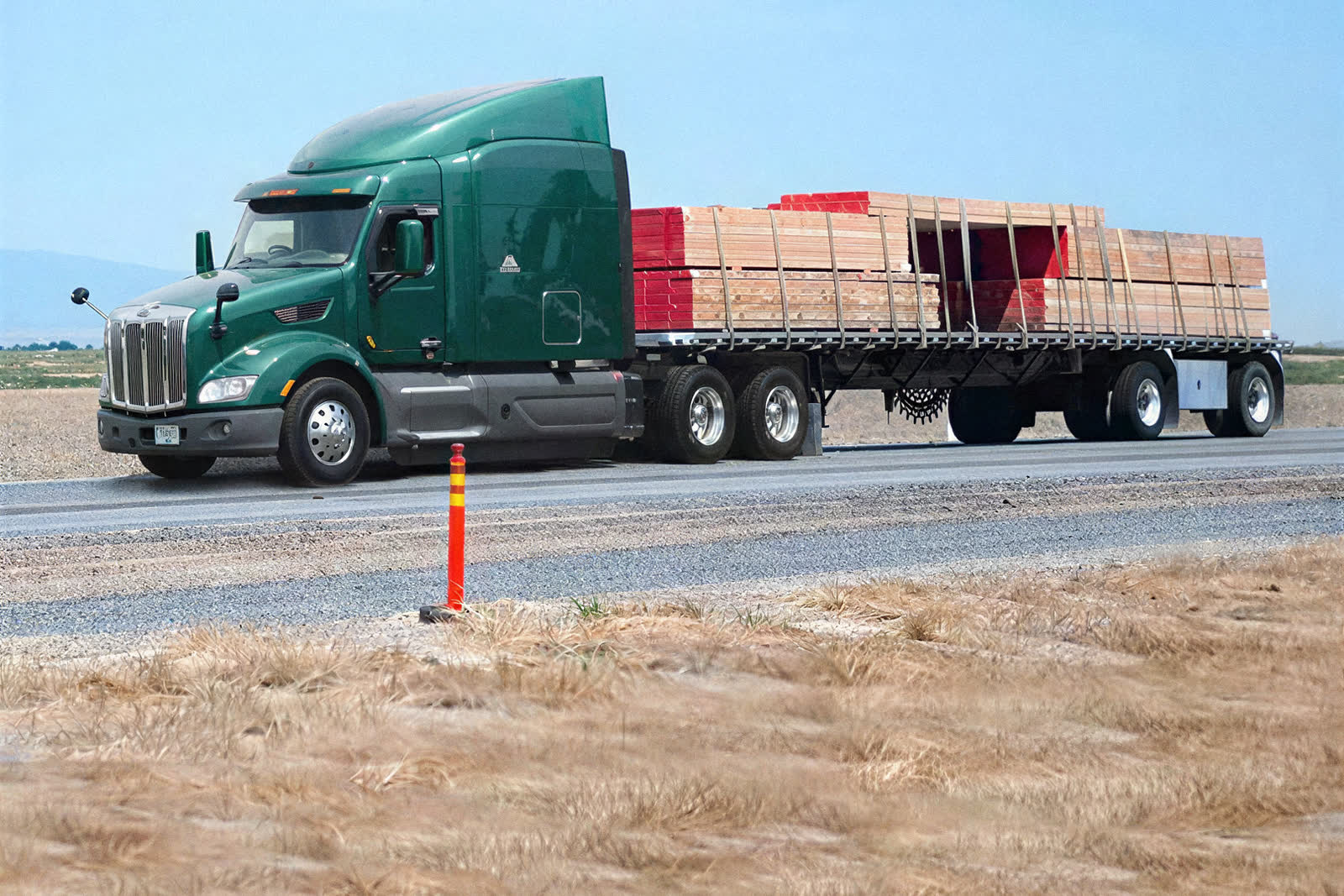 Flatbed trailer loaded with banded lumber on an open road