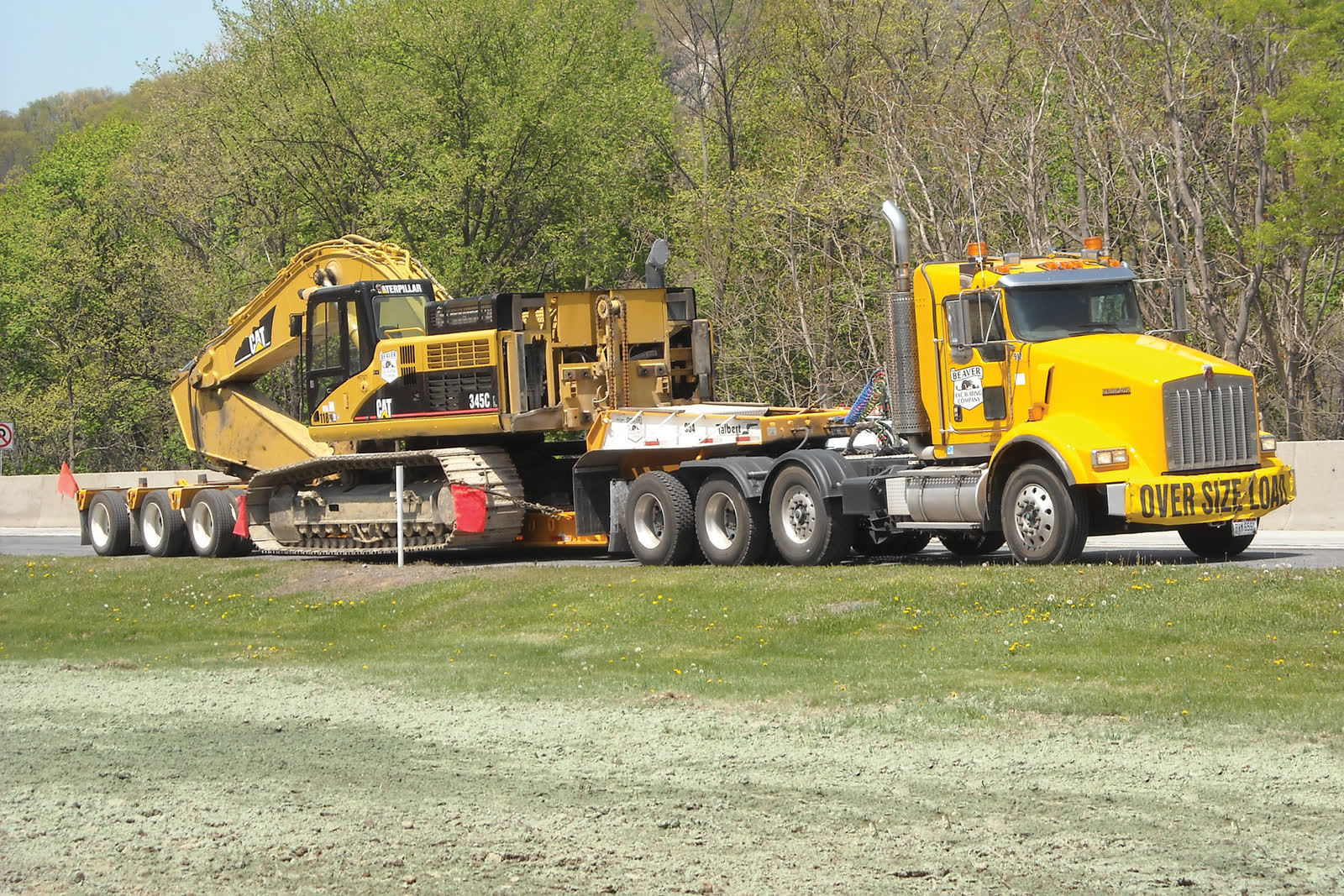 Tracked excavator secured on a lowboy trailer behind a tractor unit